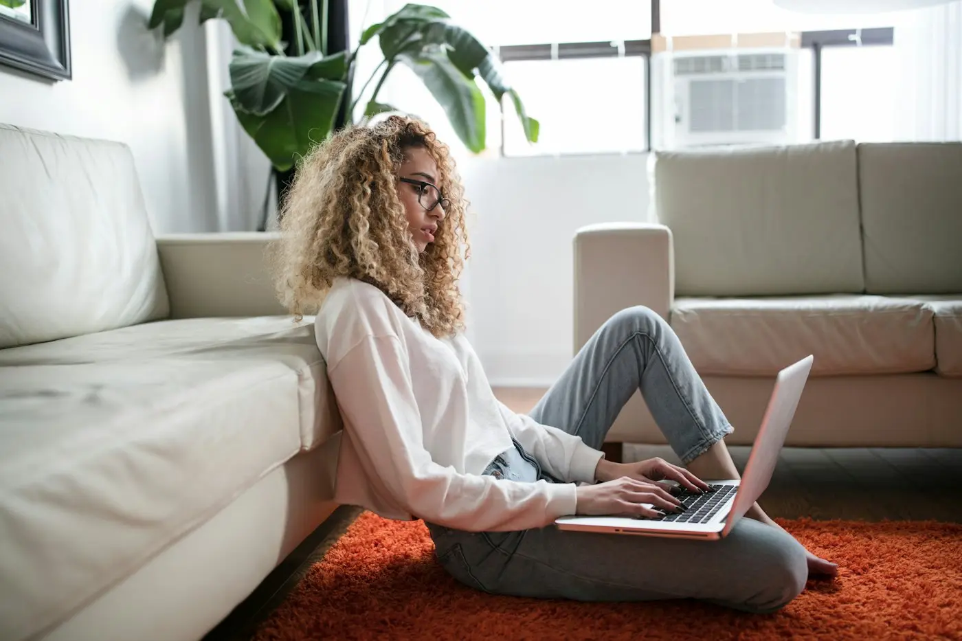 A woman working on a laptop on her living room floor
