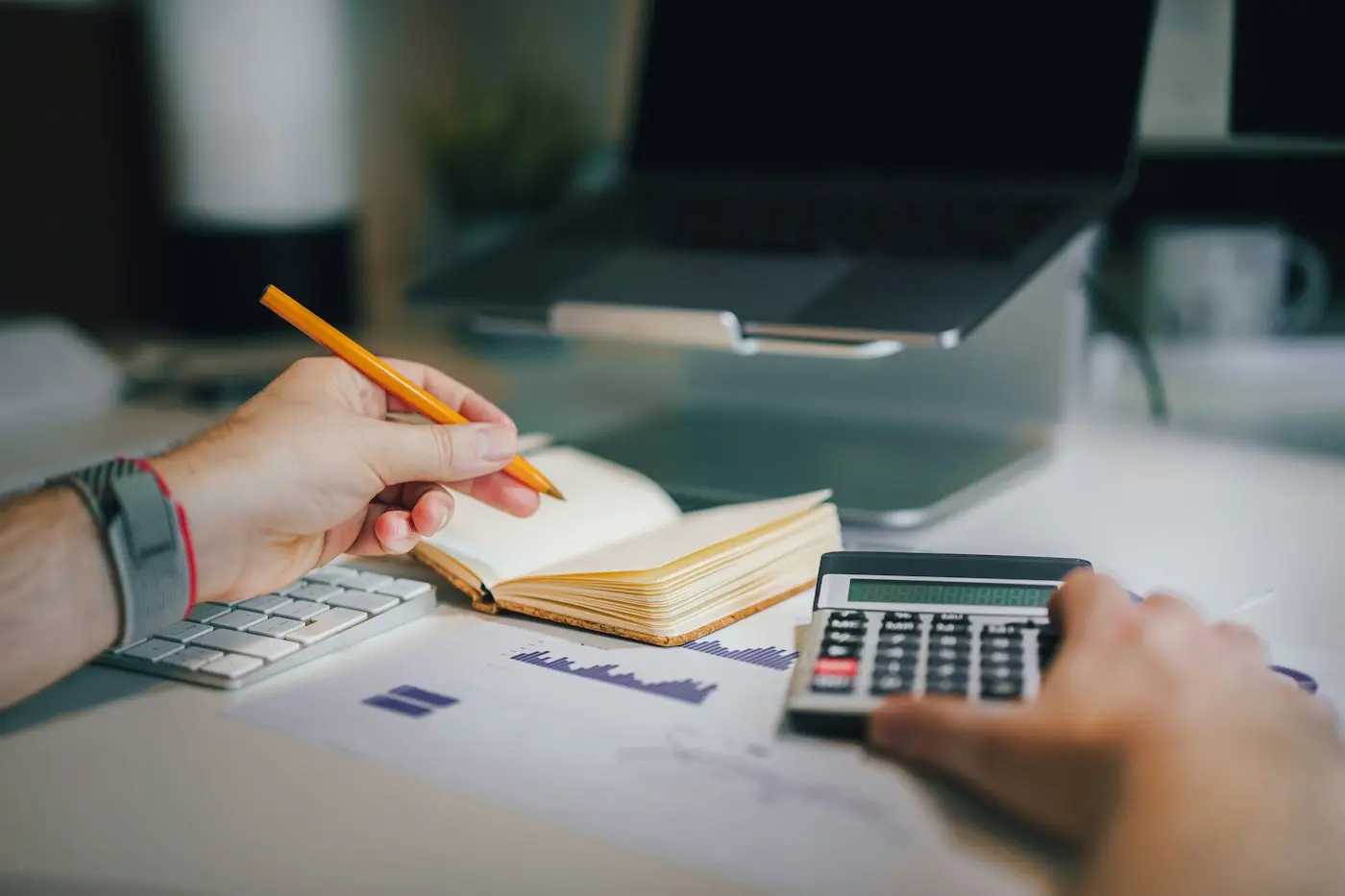 A person at a desk with a calculator and a notebook
