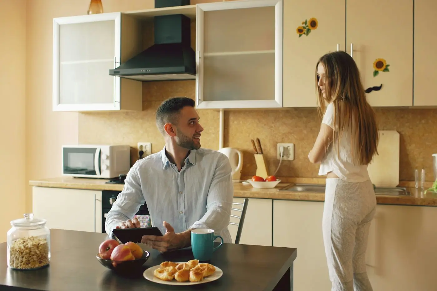 A couple talking across the kitchen table in the morning